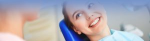 Young woman sitting in dentist office and looking at her doctor with smile 